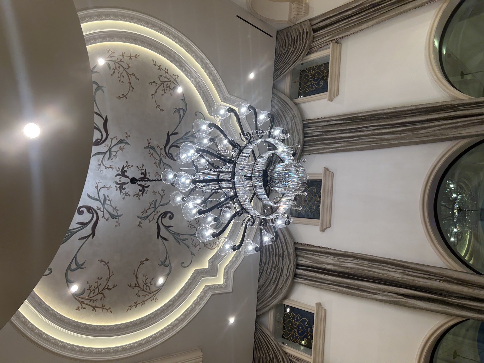 Chandelier and cove lighting under a hand-painted dome ceiling